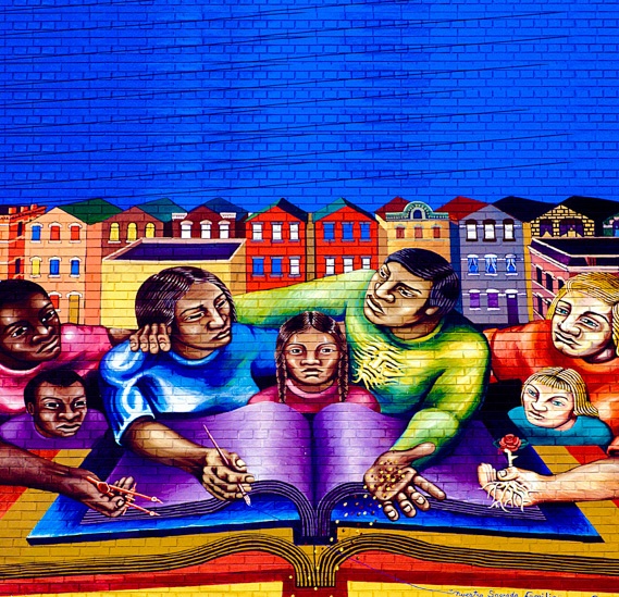 A mural of a community standing over a book