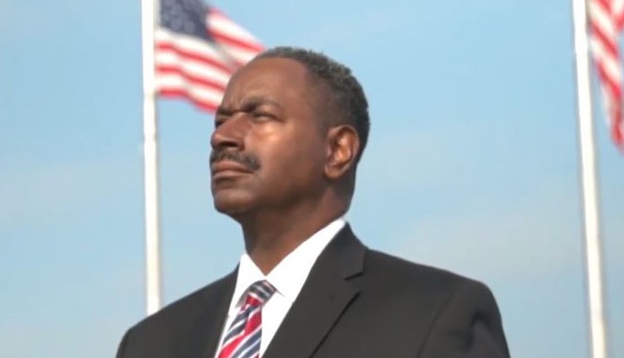 Ray Moore in front of American flags