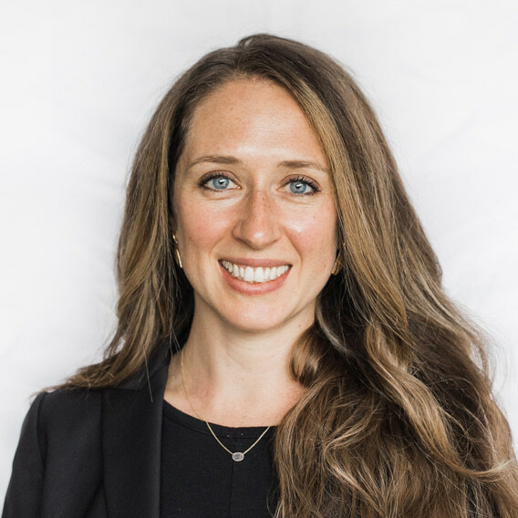 Rebecca Livengood is a white woman in her late thirties with long brown hair. She is wearing a black shirt and black blazer and is smiling.