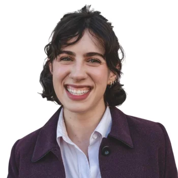 White woman in violet coat smiling