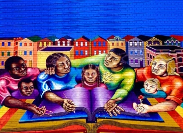 A mural of a community standing over a book